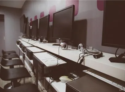 Rangée d'ordinateurs avec écrans noirs, casques et claviers dans une salle sombre à Toulouse en Haute-Garonne 31