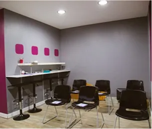 Salle de réunion moderne avec murs gris, barre haute blanche, chaises noires et touches magenta à Toulouse en Haute-Garonne 31