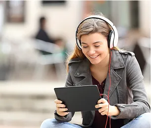 Jeune femme souriante avec un casque, regardant une tablette à l'extérieur à Toulouse en Haute-Garonne 31